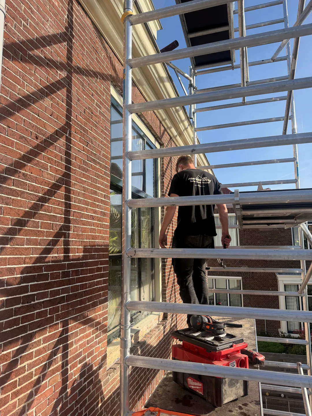 Vakman van van den Berg Totaalbouw aan het werk op de steiger aan de gevel